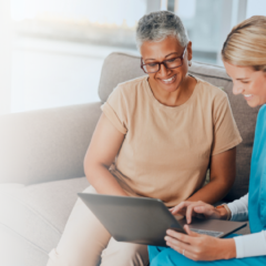 Caregiver and senior woman smiling while reviewing information on a laptop at Orchard Heights Assisted Living.